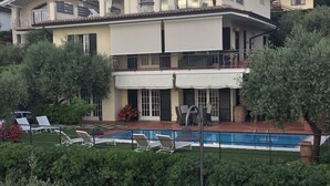 Ein zweistöckiges Haus mit Swimmingpool, Balkon und einer Steinsäule im Vordergrund.