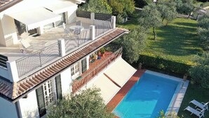 Ein modernes Haus mit Swimmingpool, überdachter Terrasse und einem gepflegten Garten.