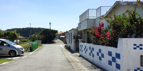 Una calle residencial con casas, un coche aparcado y un cielo despejado.