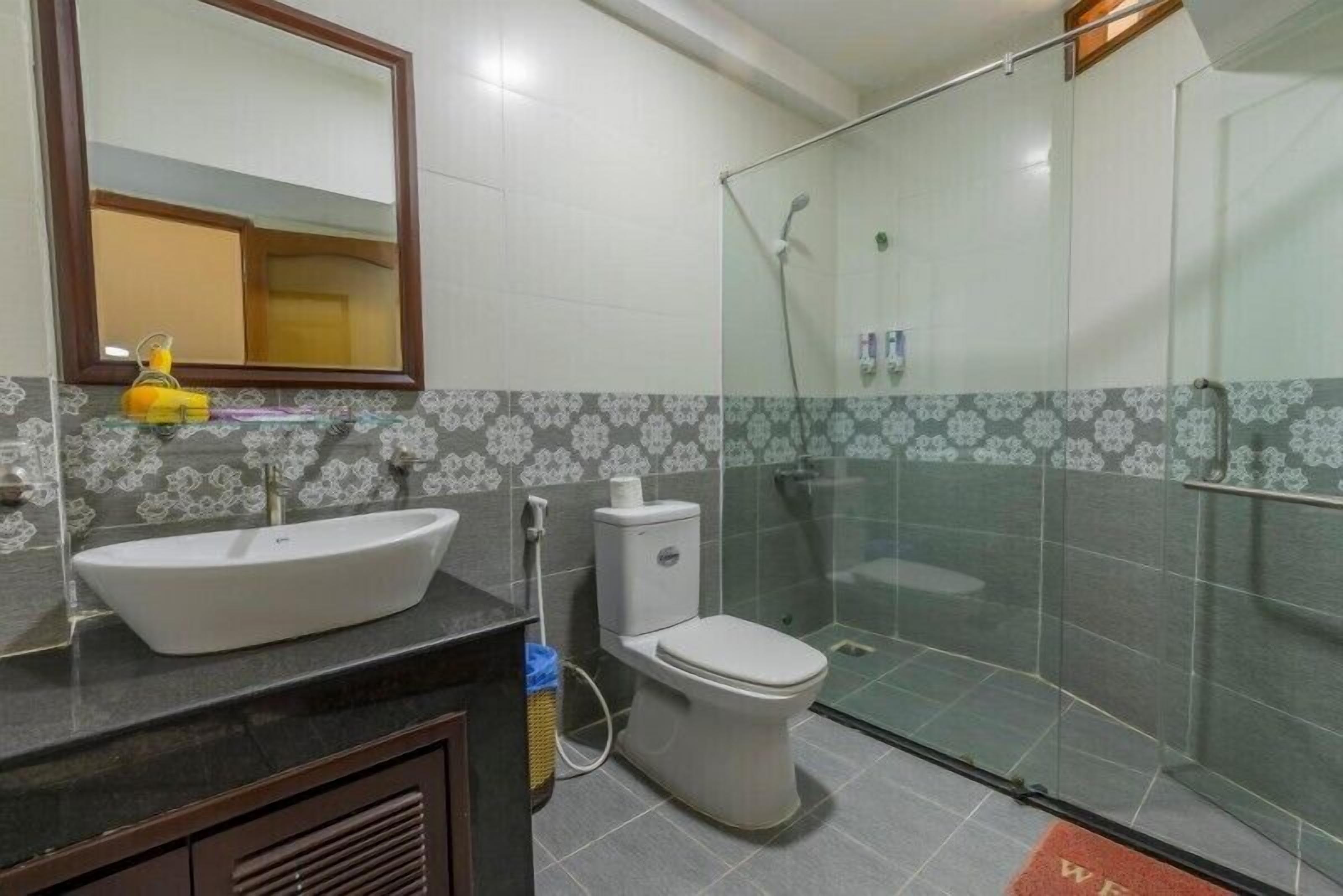 Un baño con lavamanos blanco, inodoro y ducha con mampara de vidrio.