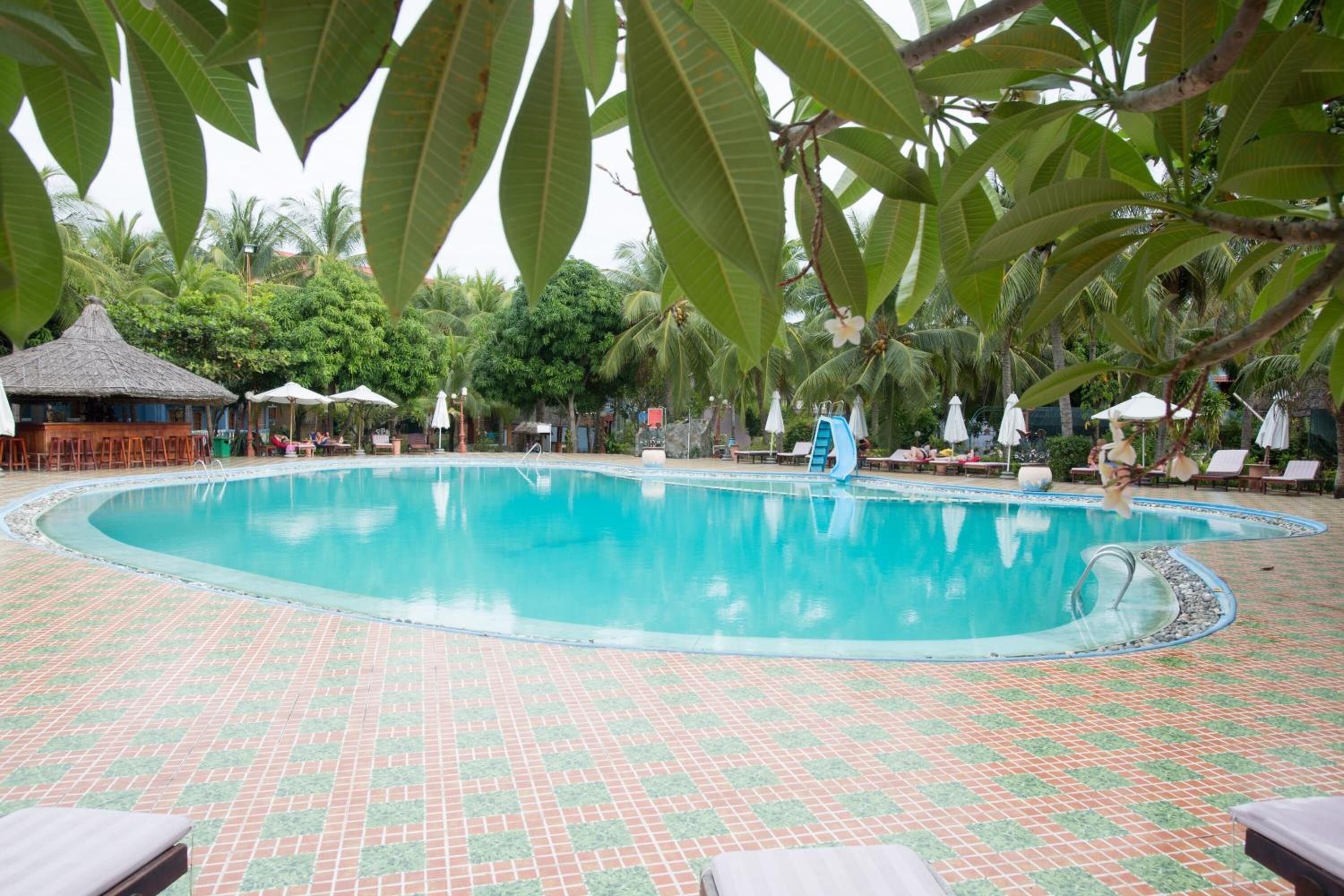 Une piscine dont le fond est carrelé et qui est équipée de chaises longues.