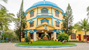 Un edificio grande y amarillo con una cúpula azul y un balcón, identificado como 'Palmera Resort'.