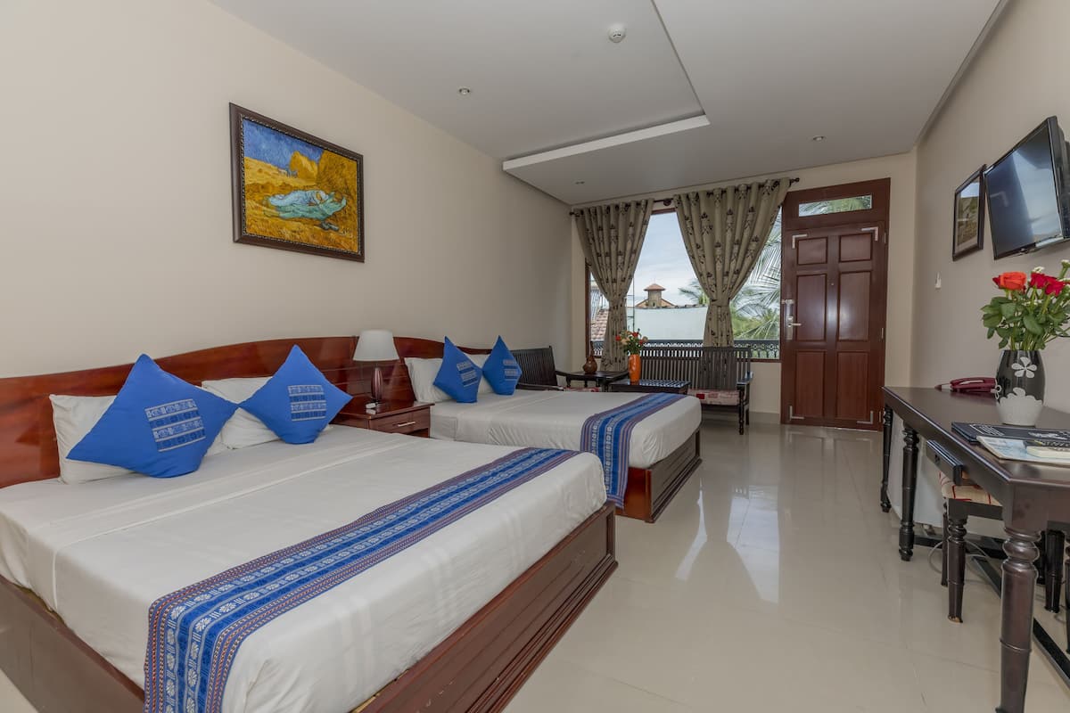 A hotel room with two beds, a desk, a chair, a TV, and a balcony with a view.