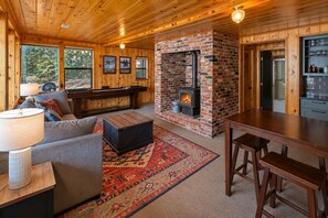 A cozy interior with a fireplace, wooden furniture, and a bar area. - Lakefront | Dock | Hot Tub | Deck | Dogs | Views (Leavenworth)