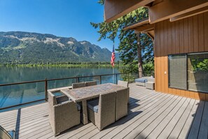 Terraço com mobiliário ao ar livre com vista para um lago e montanhas.