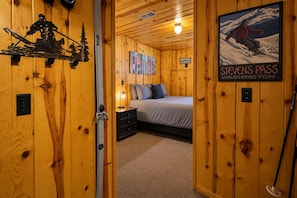 A wooden interior with a bed, a ski-themed wall decoration, and a poster of a snowboarder. - Lakefront | Dock | Hot Tub | Deck | Dogs | Views (Leavenworth)