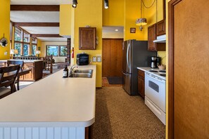 A kitchen with a central island, wooden cabinets, a stainless steel refrigerator, and a stove. - Lakefront | Dock | Hot Tub | Deck | Dogs | Views (Leavenworth)