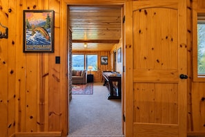 A wooden interior with a couch, a pool table, and a framed picture on the wall.