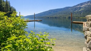 Un lac aux eaux limpides, bordé de quais en bois qui s’avancent dans l’eau, entouré d’une végétation luxuriante et avec des montagnes en toile de fond.