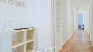 Ein Flur mit weißer Wand und Holzboden. Eine weiße Regaleinheit mit einigen Gegenständen darauf.