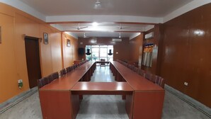 A conference room with a long table and chairs, white walls, and ceiling fans. - Centennial Hotel 2008 (Phuntsholing)