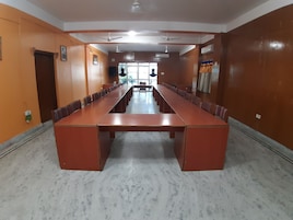 A conference room with a long table and chairs, white walls, and ceiling fans.