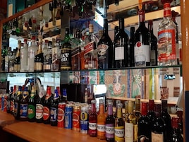 A bar with shelves stocked with various bottles of alcohol, including liquor, wine, and beer.