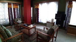 A living room with a sofa, armchairs, a coffee table, and a television. - Centennial Hotel 2008 (Phuntsholing)