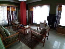 A living room with a sofa, armchairs, a coffee table, and a television.