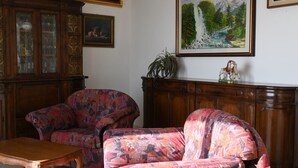 Ein Zimmer mit zwei gestreiften Sofas, einer Holzkabine und einem Gemälde eines Wasserfalls.