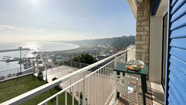 Ein Balkon mit Meerblick, eine gepflasterte Fläche und ein Tisch mit Tischdecke.