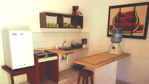 Eine kleine Küche mit Kühlschrank, Herd, Spüle und einem Barhocker.
