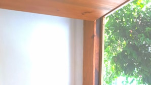 Ein kleines Zimmer mit einem Holztisch, einem Stuhl und einem Fenster mit Blick auf Grünflächen.