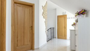 A hallway with wooden doors, a stone wall, and a white cabinet with flowers. - APARTMENT ST. PETR OLD in SPLIT Downtown WITH GREAT SUNY TERRACE, area of ​​76m2 (Split)