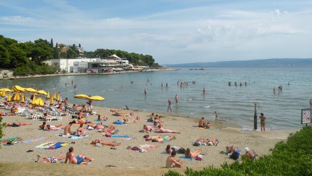 A beach with people sunbathing and swimming, umbrellas, and a building in the background. - APARTMENT ST. PETR OLD in SPLIT Downtown WITH GREAT SUNY TERRACE, area of ​​76m2 (Split)