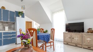 A modern kitchen with blue cabinets, a dining table with chairs, a TV, and a decorative vase with flowers. - APARTMENT ST. PETR OLD in SPLIT Downtown WITH GREAT SUNY TERRACE, area of ​​76m2 (Split)