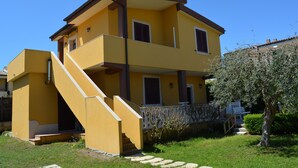 A two-story yellow building with a balcony on the upper floor and a staircase leading to the entrance. - Villa Lu Calabernardo (Contrada Calabernardo)