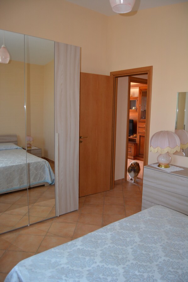 Un dormitorio con cama, cómoda, espejo y puerta que da a un baño.
