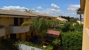A residential building with multiple balconies, a tiled roof, and surrounding greenery including palm trees. - Villa Lu Calabernardo (Contrada Calabernardo)