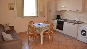 A compact kitchen with a dining table, chairs, a sofa, and a washing machine. - Villa Lu Calabernardo (Contrada Calabernardo)