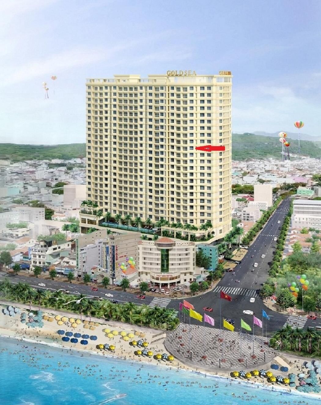 Ett högt hotell med namnet ”GOLDSEA” som har en central innergård, ligger vid stranden och erbjuder utsikt över den omgivande stadsbilden.