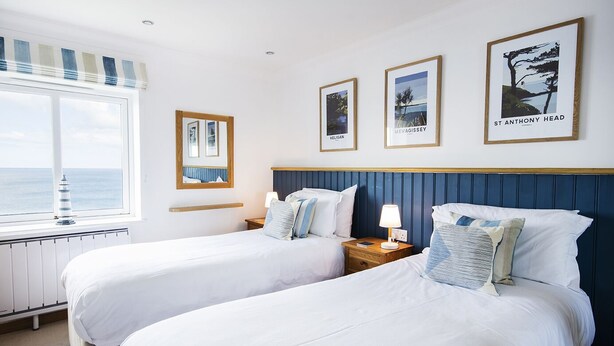 A hotel room with two beds, a view of the sea, and three framed pictures on the wall. - Marine Point, Mevagissey - sensational cliff top views of harbour and bay (Mevagissey)