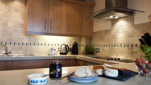A modern kitchen with wooden cabinets, a stainless steel range hood, and a tiled backsplash. - Marine Point, Mevagissey - sensational cliff top views of harbour and bay (Mevagissey)