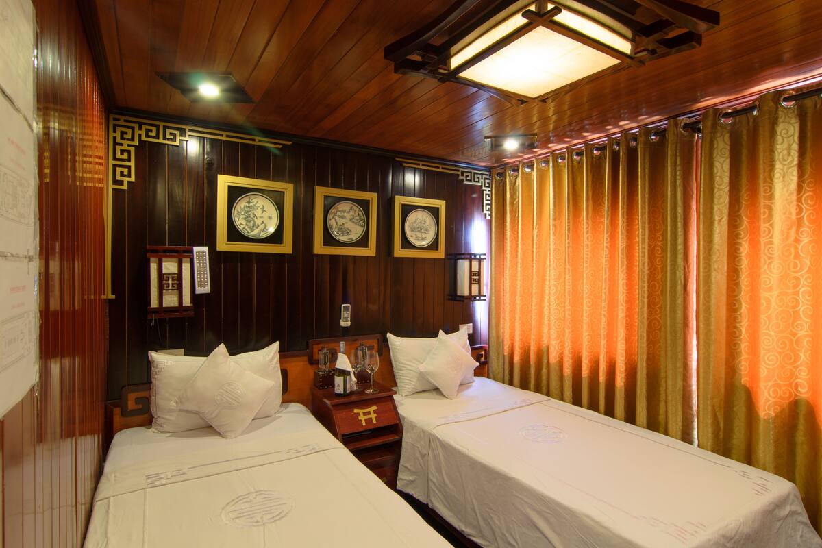 A hotel room with two beds, wooden paneling, and traditional decor.