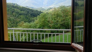 A room with a view of a mountainous landscape through a window with a white frame and a striped curtain. - A modern independent apartment with a large private terrace. (Macerata)