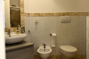A bathroom with a sink, bidet, toilet, and a mirror. - S068 - Sirolo, new two-room apartment with terrace (Sirolo)