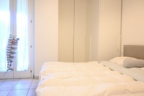 A bedroom with a bed, a wardrobe, and a door with a view. - S068 - Sirolo, new two-room apartment with terrace (Sirolo)