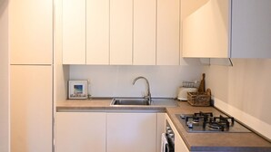 Een kleine keuken met een spoelbak, fornuis en kastjes.