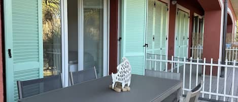 Un espacio al aire libre cubierto con zona de comedor, una mesa, sillas, una escultura decorativa de animal y una valla blanca.
