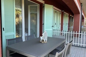 Uma área de refeições ao ar livre coberta, com mesa e cadeiras, uma escultura decorativa de animal e um cercado branco.