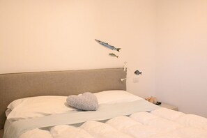 A bed with a heart-shaped pillow, a headboard, and wall-mounted fish decorations. - S068 - Sirolo, new two-room apartment with terrace (Sirolo)