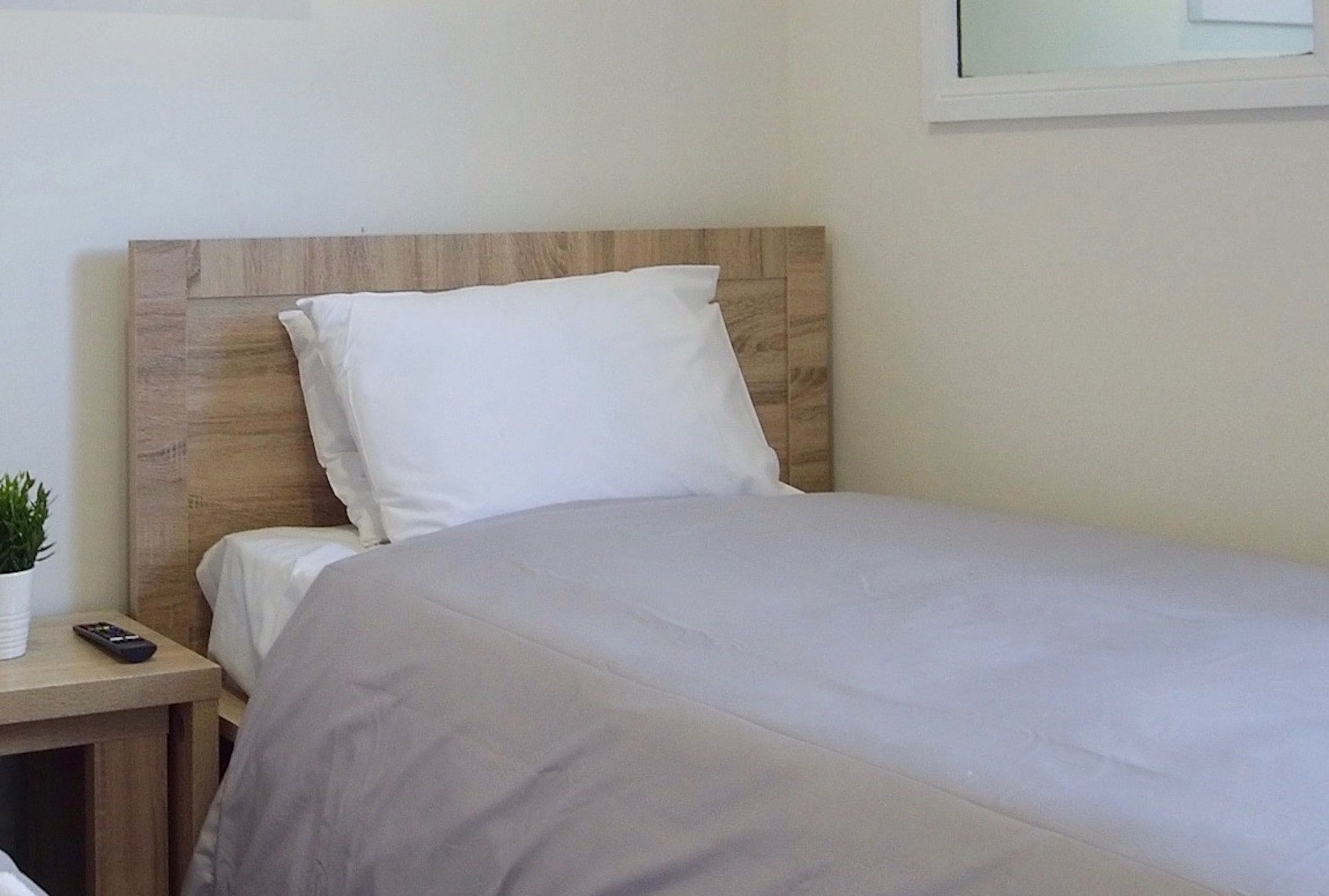 A neatly made bed with a wooden headboard and white bedding.