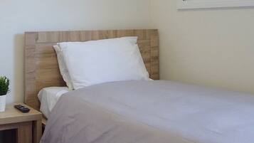 A neatly made bed with a wooden headboard and white bedding.
