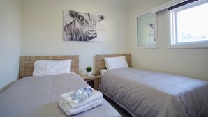 A hotel room with two beds, a nightstand, a window, and a painting on the wall. - Argyle Hotel Southern Highlands (Moss Vale)