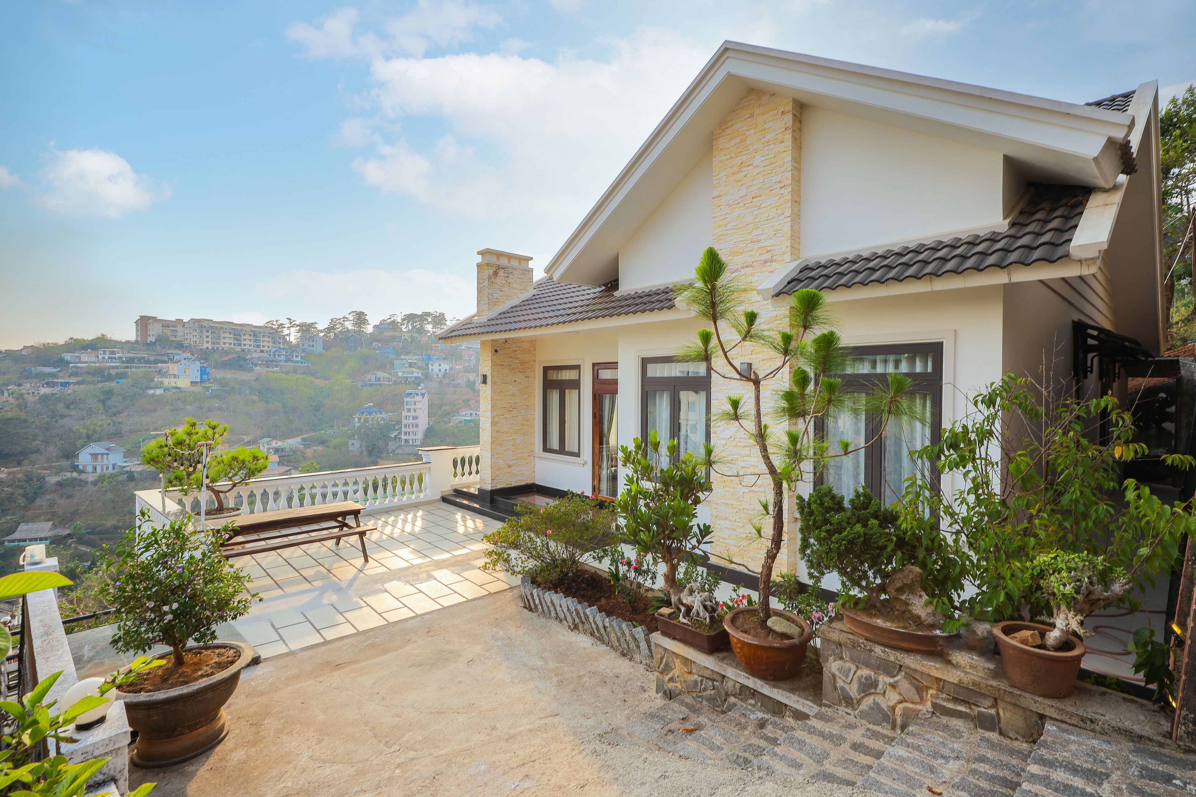 A house with a balcony, potted plants, and a view of the surrounding area.