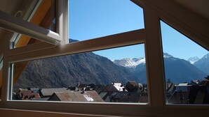 A view through a window with a mountain landscape, including snow-capped peaks and a village below. - MODERN DUPLEX APARTMENT? CENTRAL LOCATION - SLEEPS 5 (Le Bourg-d'Oisans)
