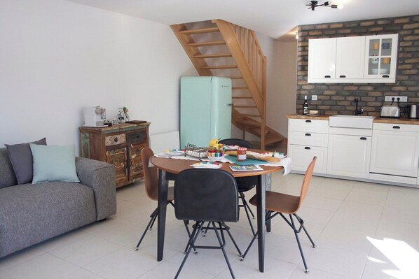 A compact living space with a dining area, a sofa, a staircase, and a kitchen with white cabinets. - MODERN DUPLEX APARTMENT? CENTRAL LOCATION - SLEEPS 5 (Le Bourg-d'Oisans)