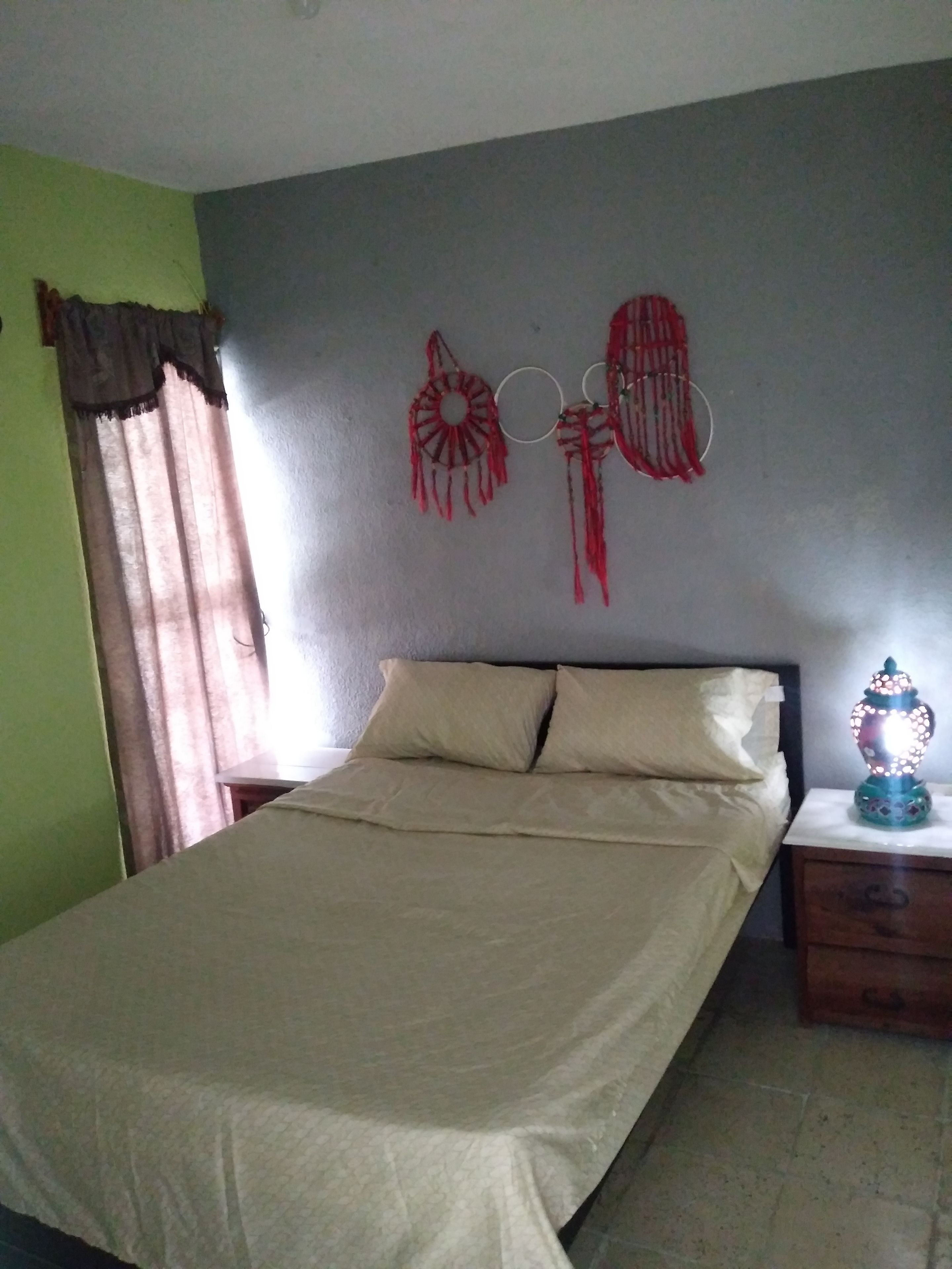 Un dormitorio con cama, mesita de noche, lámpara y adornos en la pared.