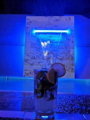 A glass of water with ice and a lemon slice on a bar counter with a blue-lit background. - Casa Ackal Huitz (Ciudad Valles)
