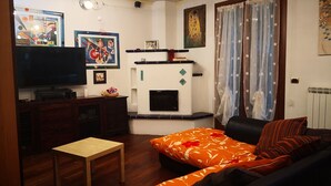Ein Wohnzimmer mit einer Couch, einem Fernseher, einem Kamin und Kunstwerken an den Wänden.